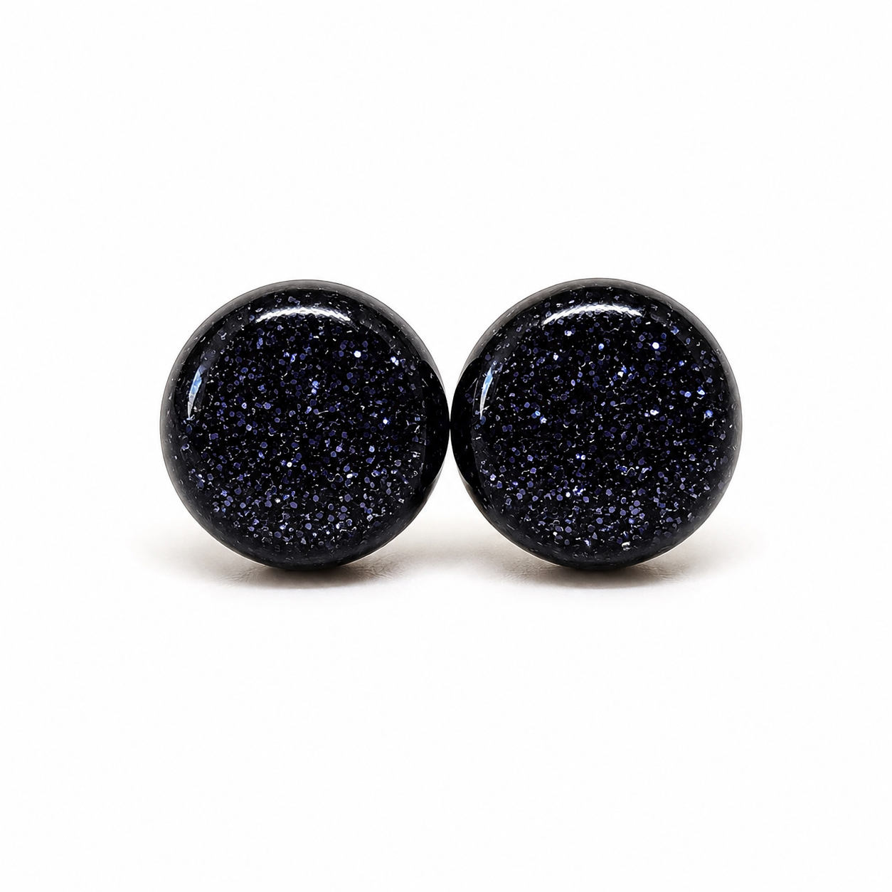 Pair of black glittery round earrings on a white background