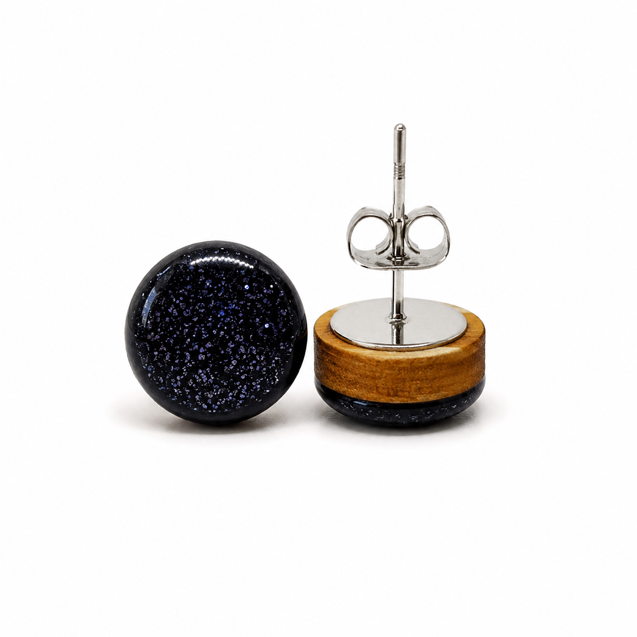 Pair of earrings with black speckled design and wooden base on a white background