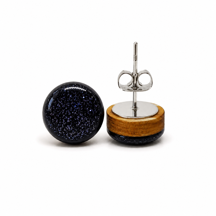Pair of earrings with black speckled design and wooden base on a white background
