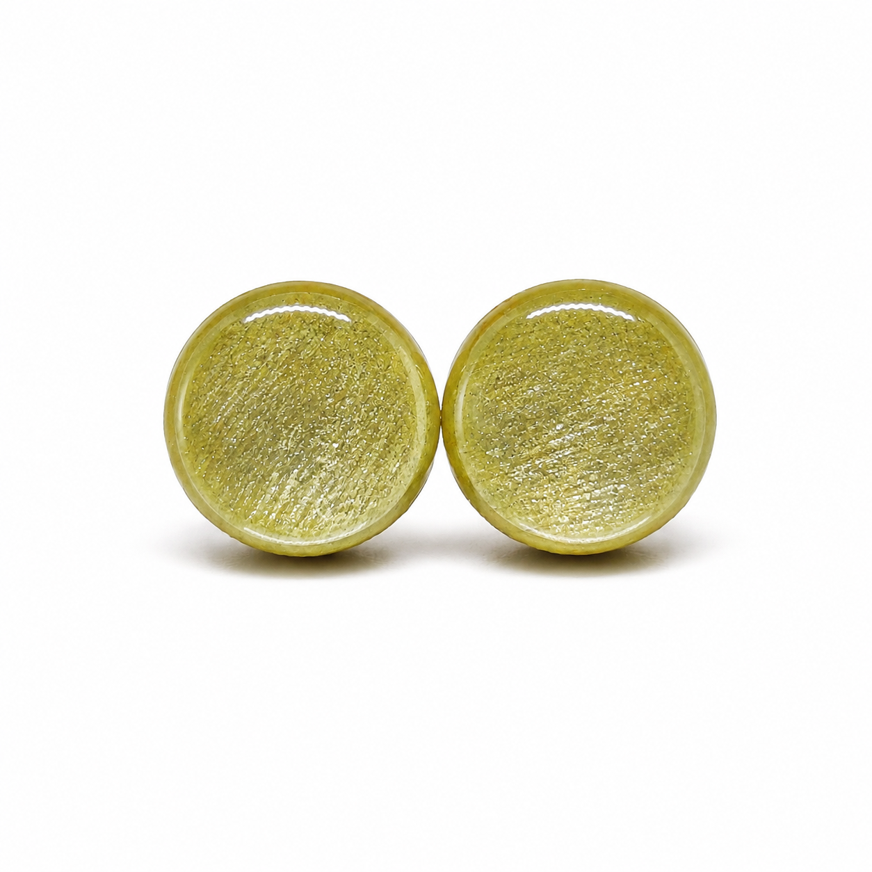 Pair of round, sage green shimmery colored earrings on a white background