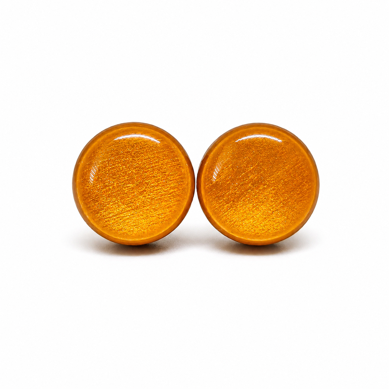 Pair of round yellow gold shimmery earrings on a white background