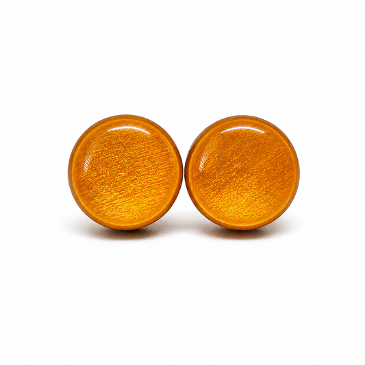 Pair of round yellow gold shimmery earrings on a white background