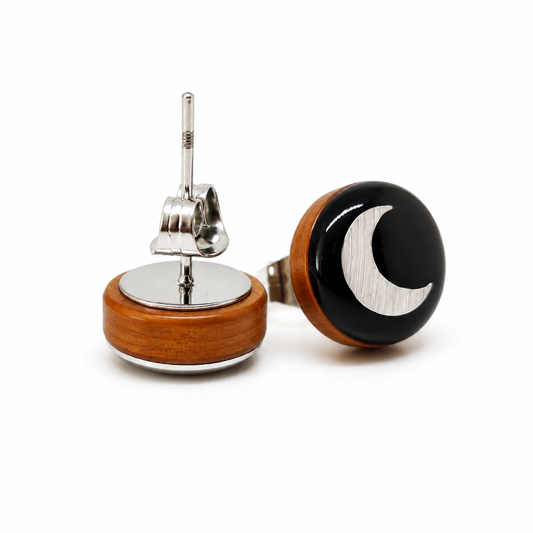Pair of earrings with wooden base, silver middle, and black and white crescent moon design on a white background.