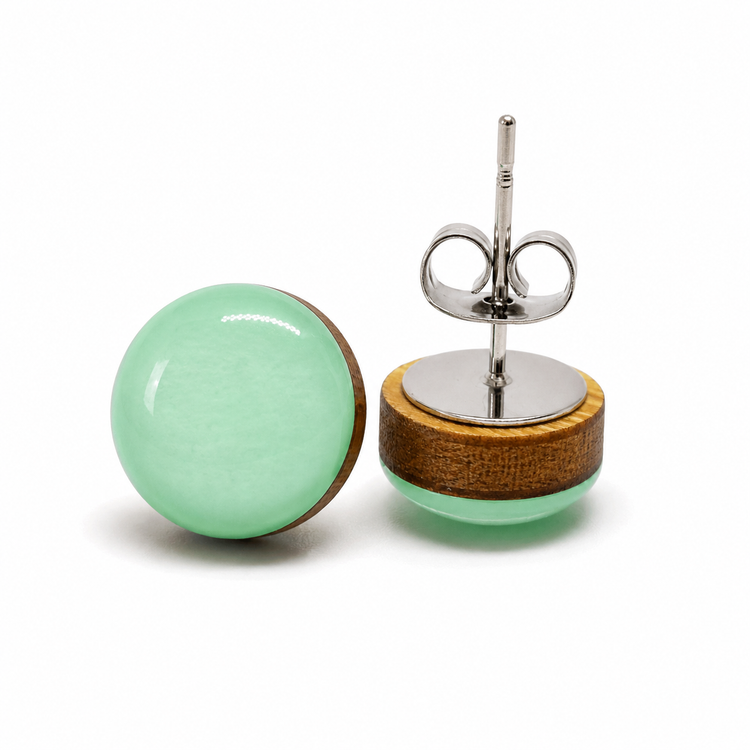 Pair of earrings with green round stones and wooden bases on a white background