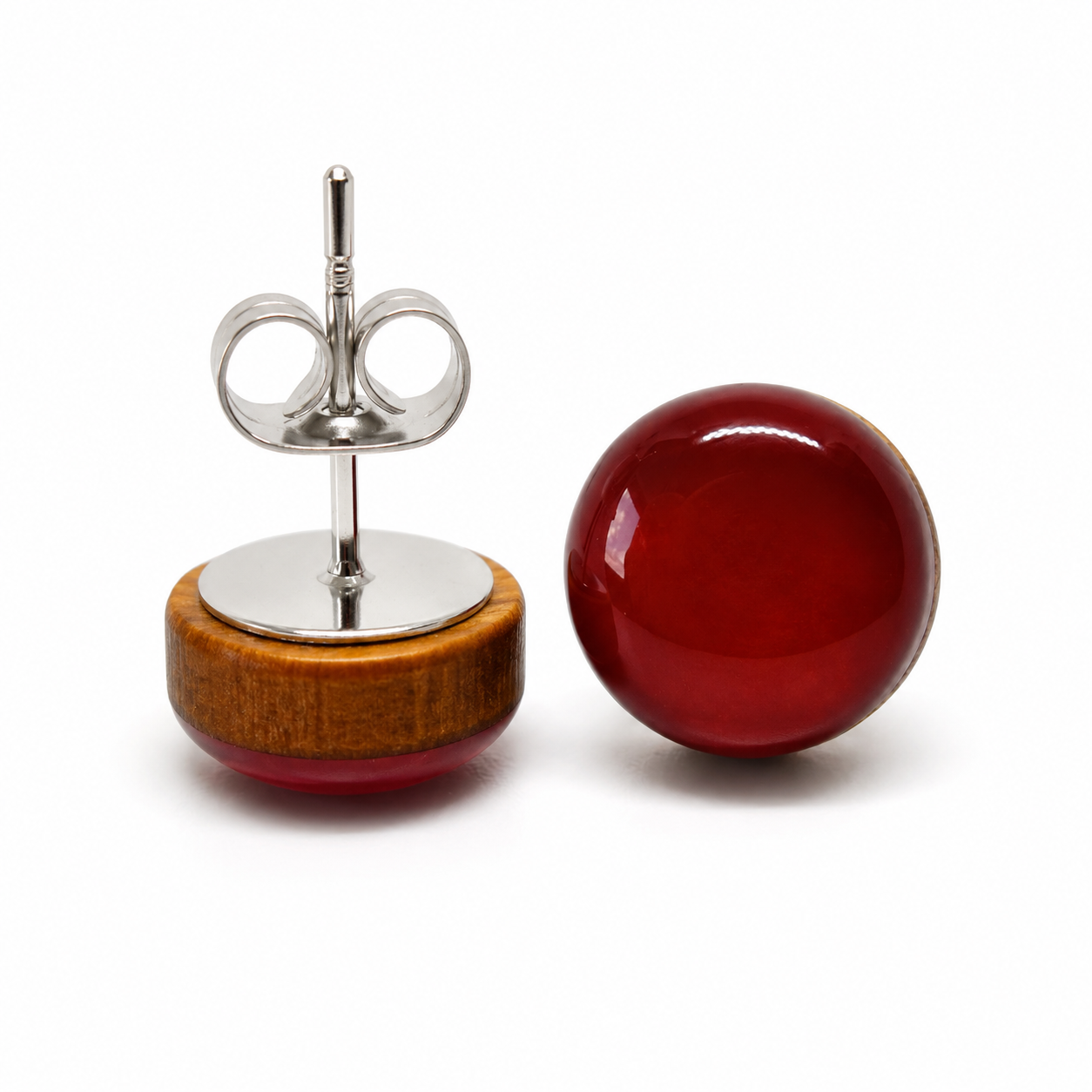 Pair of earrings with wooden base and red gemstone on a white background