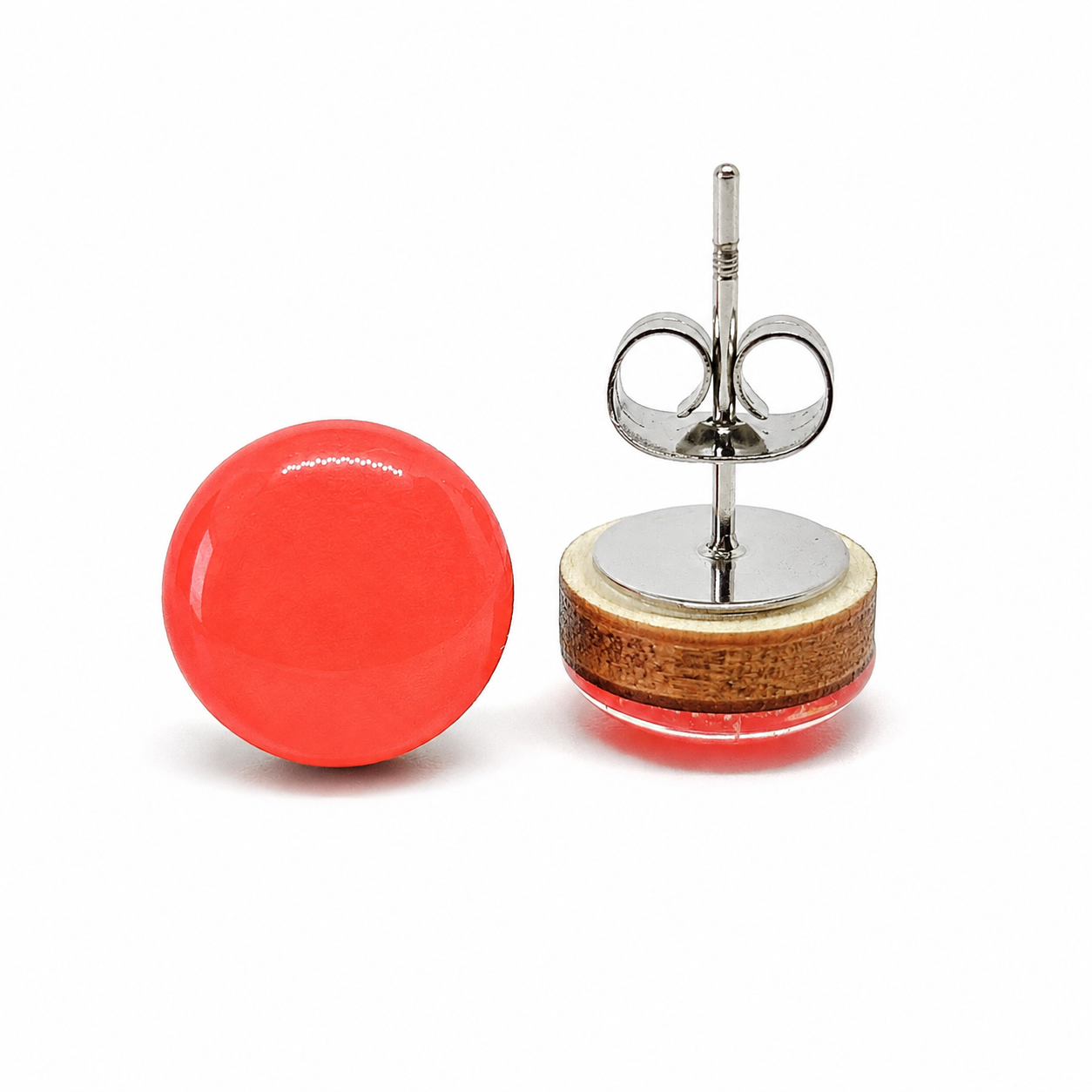 Pair of earrings with a red round stone and wooden base on a white background